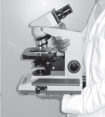 Proper handling of a microscope. Both hands are used when carrying this delicate instrument.